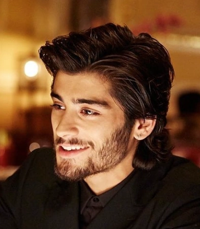 Medium-length, wavy hair styled in a voluminous quiff; dark brown color; suitable for casual or formal occasions.