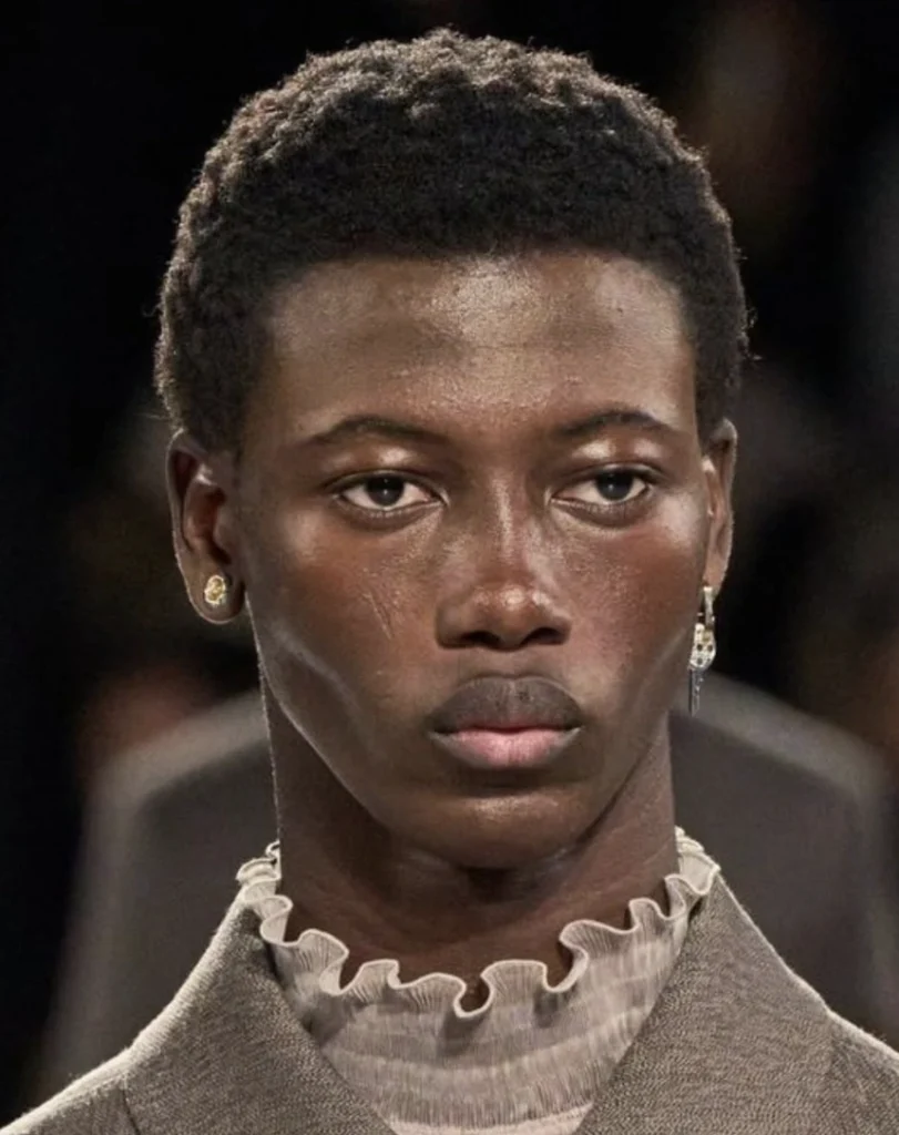 Close-cropped hairstyle with short, textured curls. Natural dark color, suitable for casual or formal occasions.